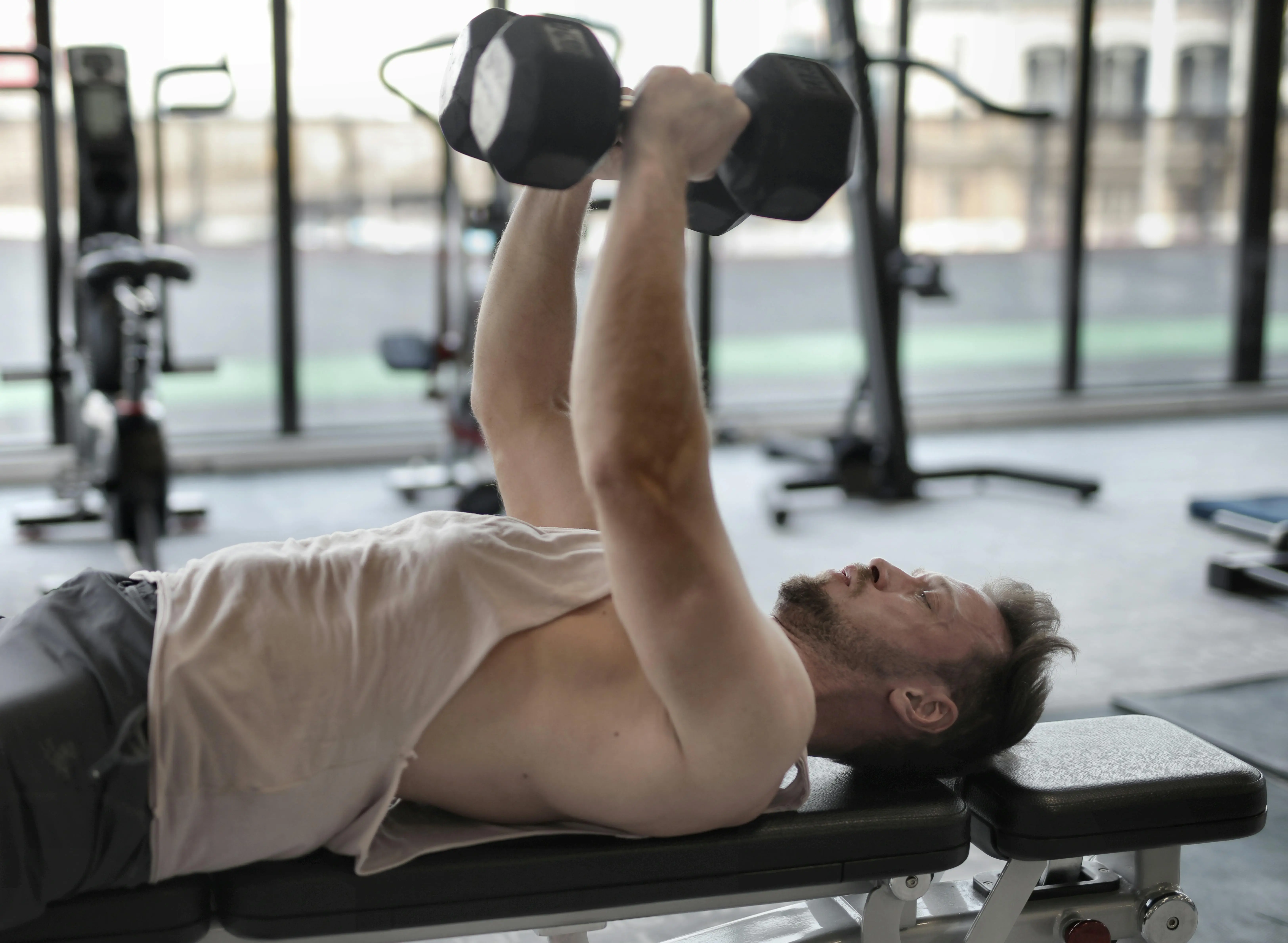 man laying on a bench lifting weights above his chest